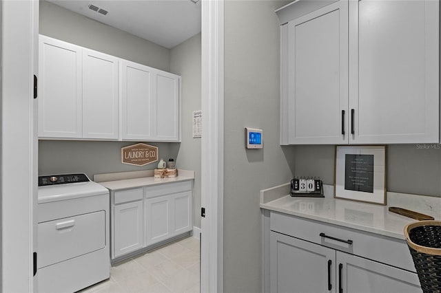 kitchen featuring washer / dryer and white cabinets