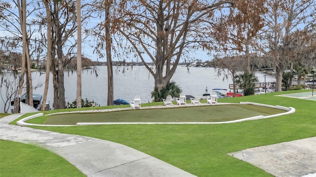 surrounding community with a water view and a lawn