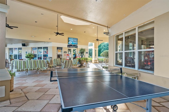 game room with a towering ceiling, a textured ceiling, and a skylight