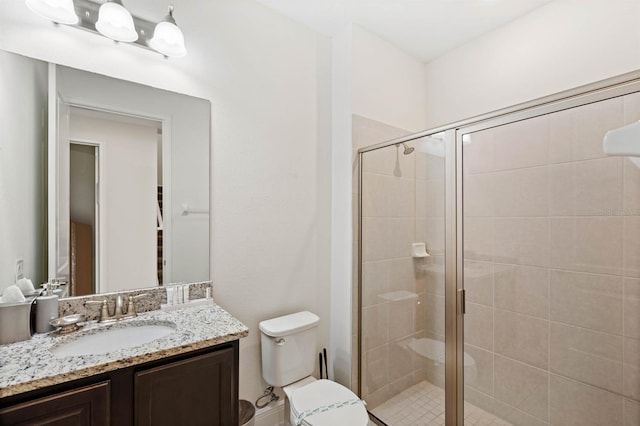 bathroom with an enclosed shower, vanity, and toilet