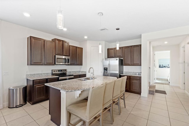 kitchen with pendant lighting, sink, a kitchen island with sink, dark brown cabinetry, and stainless steel appliances