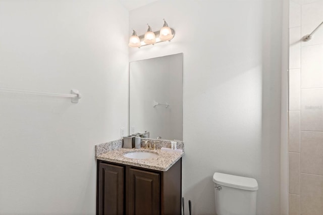 bathroom with vanity, a tile shower, and toilet