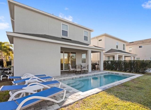 rear view of house with a yard, a fenced in pool, and a patio