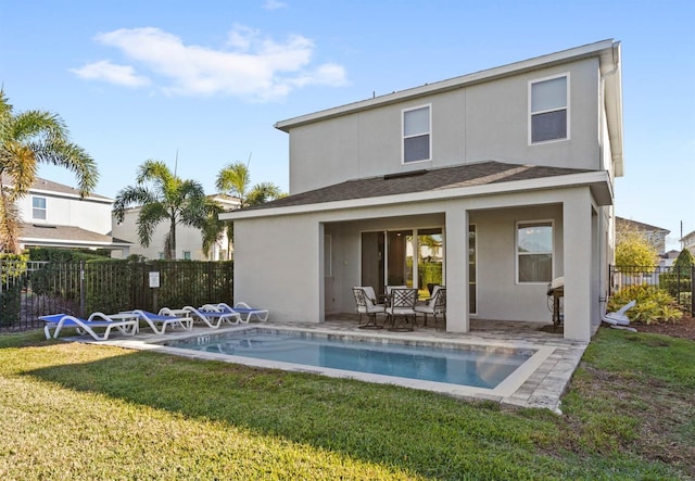 rear view of property with a fenced in pool, a patio area, and a lawn