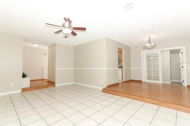 empty room featuring ceiling fan with notable chandelier and light tile patterned floors