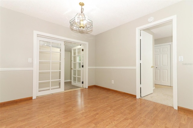 empty room with a textured ceiling and light hardwood / wood-style flooring