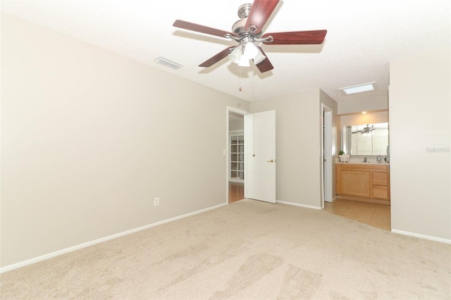 unfurnished bedroom with ensuite bathroom, light carpet, and ceiling fan