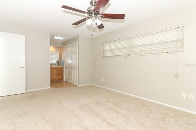 unfurnished bedroom with ensuite bathroom, ceiling fan, and light carpet