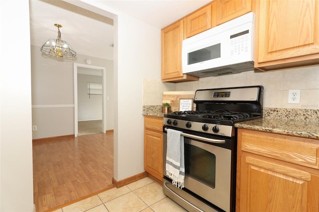 kitchen featuring an inviting chandelier, stone counters, light tile patterned floors, backsplash, and gas range