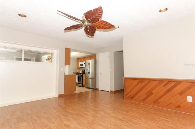 unfurnished room featuring a textured ceiling, light wood-type flooring, and ceiling fan