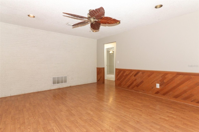 unfurnished room featuring light wood-type flooring, ceiling fan, and a textured ceiling