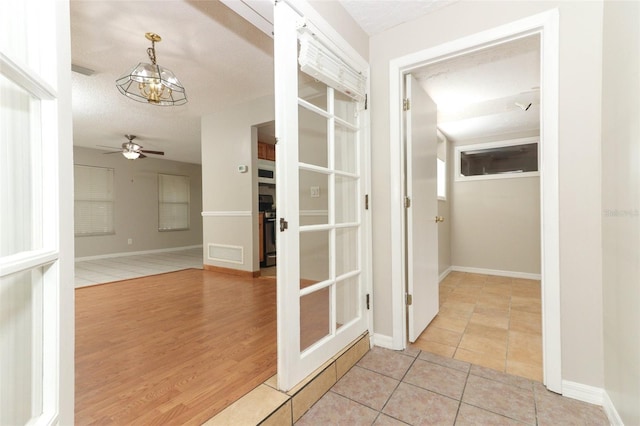 hall featuring a textured ceiling, a chandelier, and light tile patterned floors