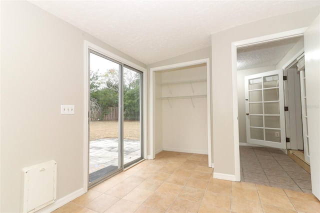 unfurnished bedroom featuring access to outside, a textured ceiling, a closet, and light tile patterned floors