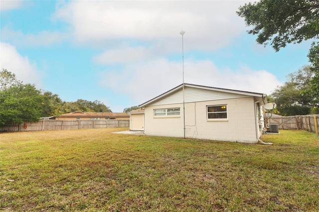 rear view of house featuring central AC and a yard