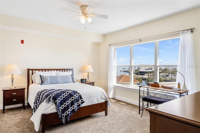 carpeted bedroom featuring a water view and ceiling fan