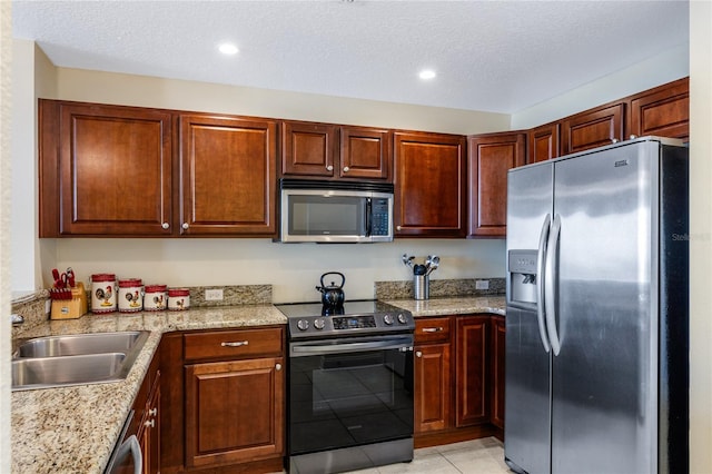 kitchen with light tile patterned floors, sink, appliances with stainless steel finishes, light stone counters, and a textured ceiling