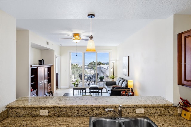 kitchen with ceiling fan, sink, a textured ceiling, and decorative light fixtures