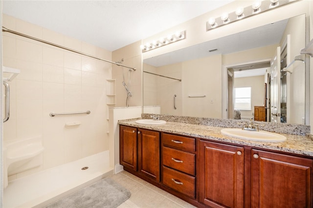 bathroom with tile patterned flooring, vanity, and a tile shower