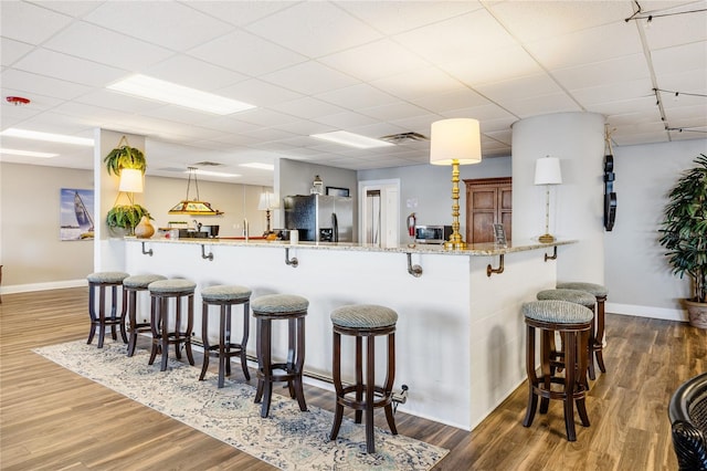 kitchen with dark hardwood / wood-style flooring, hanging light fixtures, kitchen peninsula, and appliances with stainless steel finishes