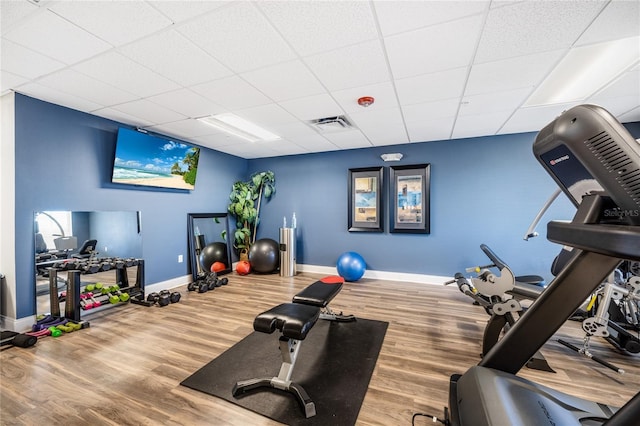 exercise area with hardwood / wood-style flooring and a paneled ceiling