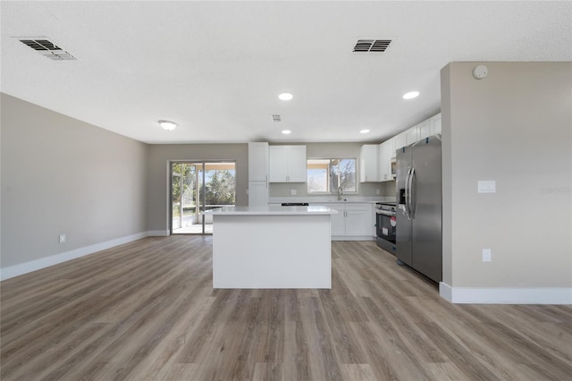 kitchen with a center island, sink, stainless steel appliances, and white cabinetry