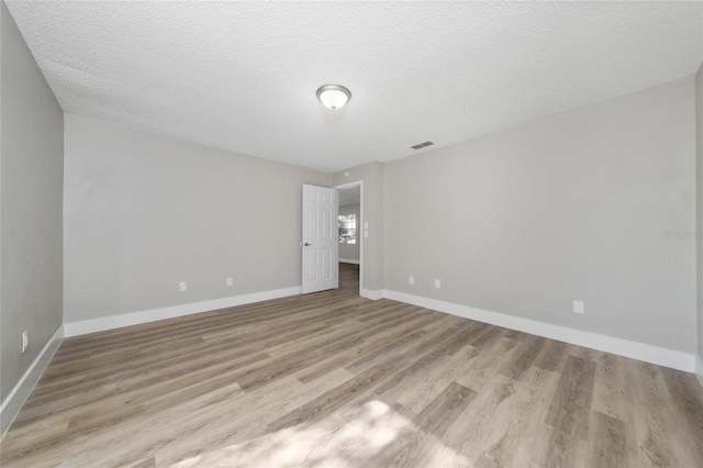 unfurnished room featuring a textured ceiling and light hardwood / wood-style flooring