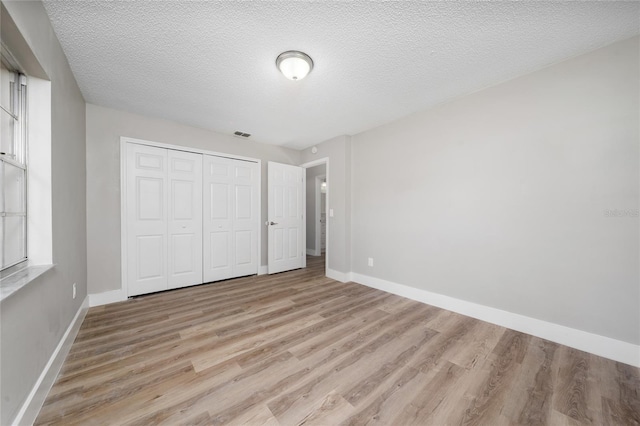 unfurnished bedroom with a closet, a textured ceiling, and light hardwood / wood-style flooring