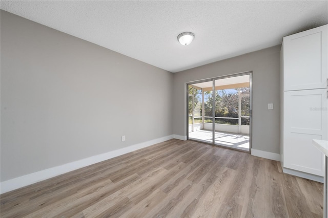 empty room featuring a textured ceiling and light hardwood / wood-style floors