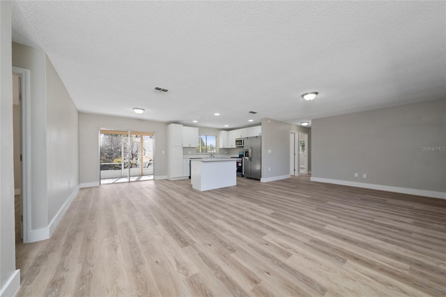 unfurnished living room with a textured ceiling and light wood-type flooring