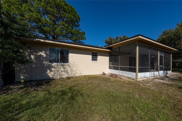 back of property featuring a yard and a sunroom