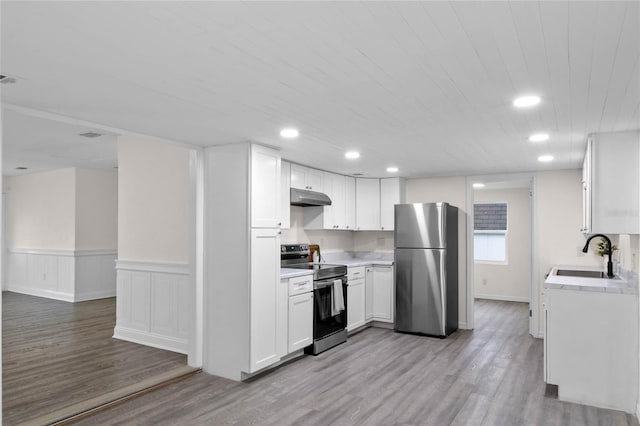 kitchen with appliances with stainless steel finishes, light hardwood / wood-style flooring, white cabinets, and sink