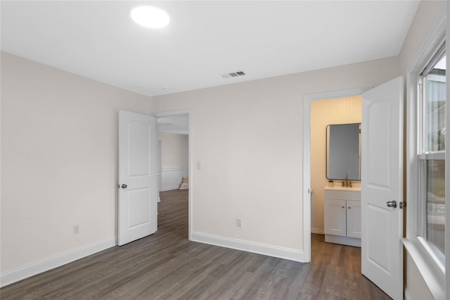 unfurnished bedroom featuring ensuite bath and dark hardwood / wood-style floors