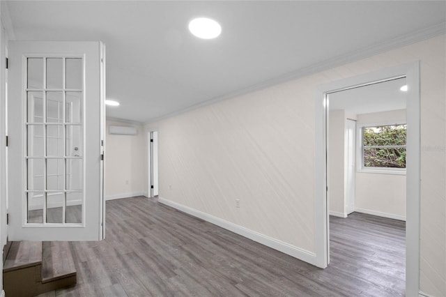 unfurnished room with a wall unit AC, wood-type flooring, and crown molding