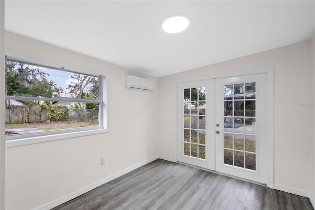 empty room with french doors, an AC wall unit, and hardwood / wood-style floors