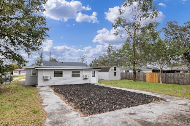 back of house with a lawn and a storage shed