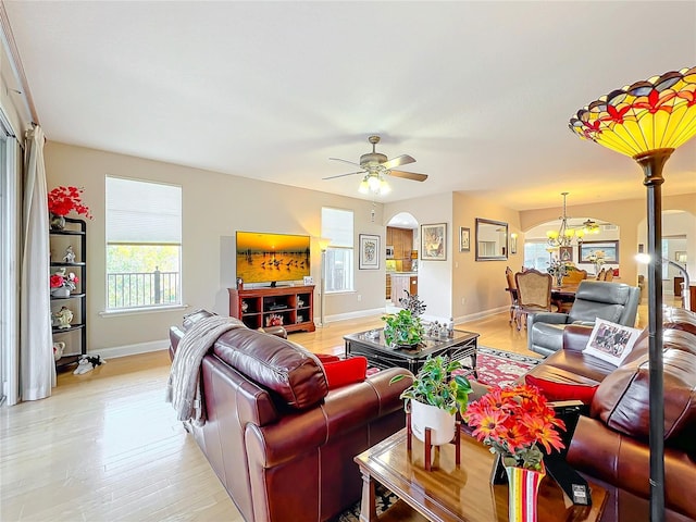 living room with ceiling fan with notable chandelier and light wood-type flooring