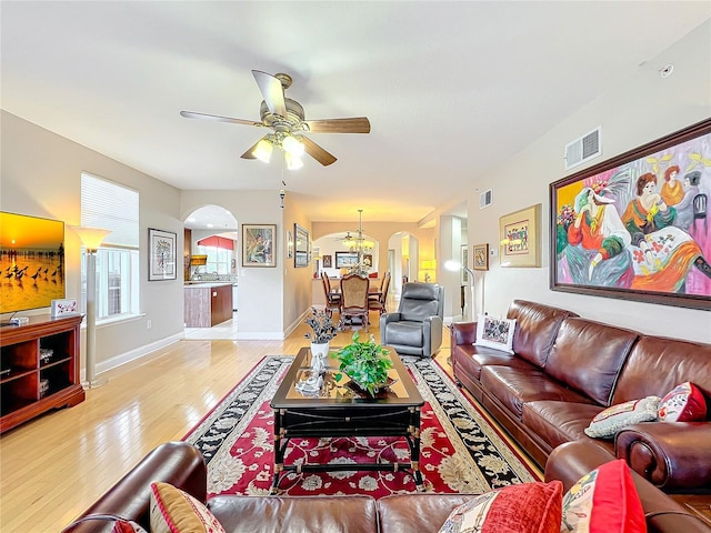 living room with ceiling fan with notable chandelier and light wood-type flooring