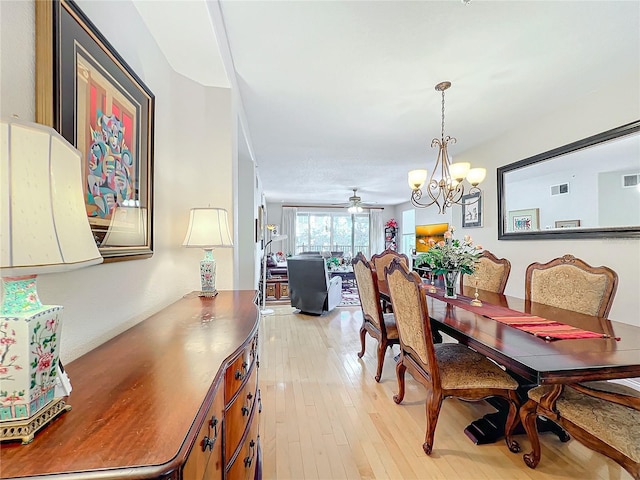 dining space with ceiling fan with notable chandelier and light wood-type flooring