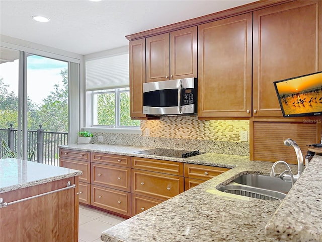 kitchen with light stone counters, sink, light tile patterned floors, and backsplash