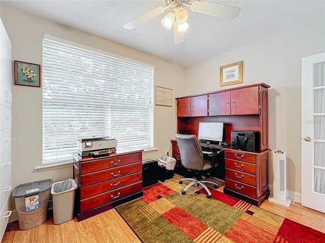 home office with ceiling fan, a wealth of natural light, a textured ceiling, and light wood-type flooring