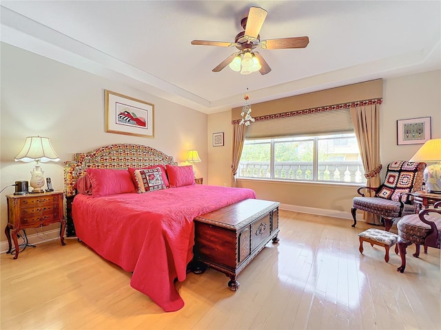 bedroom featuring ceiling fan, a tray ceiling, and light hardwood / wood-style floors