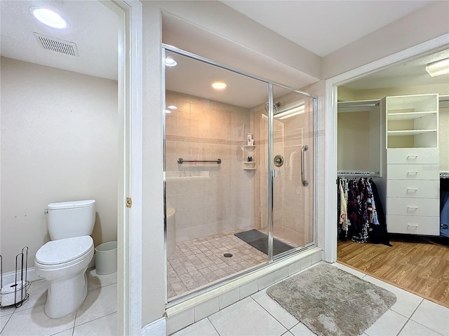 bathroom featuring tile patterned floors, toilet, and a shower with door