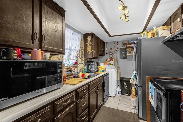 kitchen featuring stainless steel appliances, sink, light tile patterned floors, dark brown cabinetry, and a tray ceiling