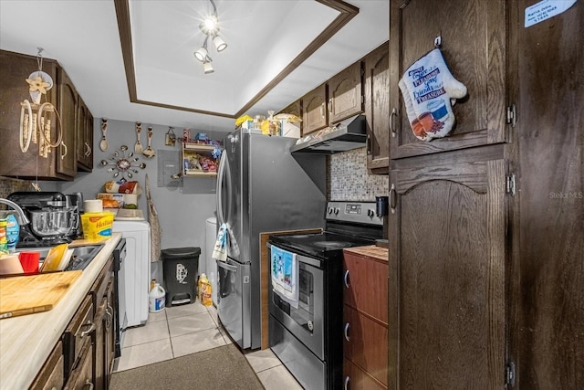 kitchen with a raised ceiling, appliances with stainless steel finishes, light tile patterned floors, sink, and washing machine and clothes dryer