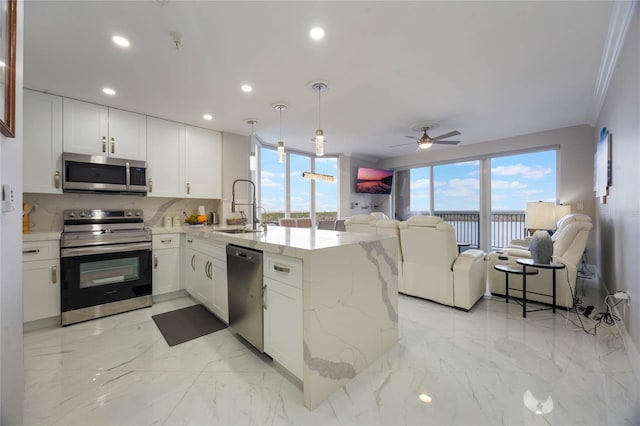 kitchen featuring appliances with stainless steel finishes, sink, white cabinets, kitchen peninsula, and light stone counters