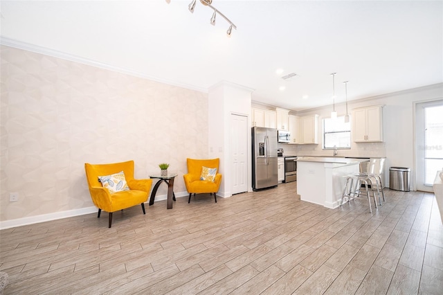 kitchen featuring a kitchen bar, crown molding, decorative light fixtures, a center island, and stainless steel appliances