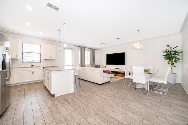 kitchen with a kitchen island, a breakfast bar, sink, and decorative light fixtures