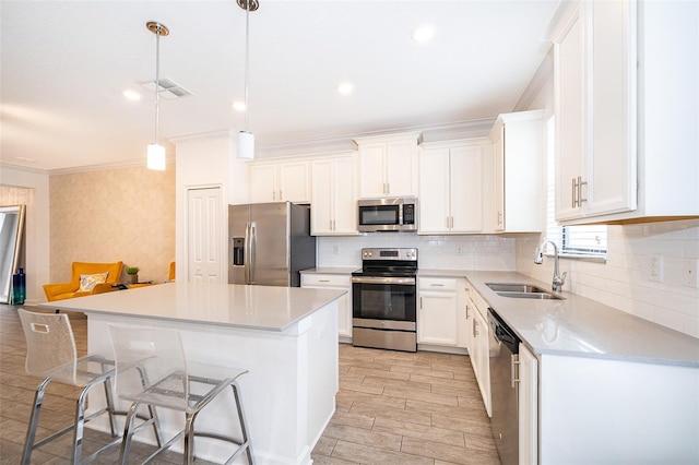 kitchen featuring pendant lighting, white cabinetry, stainless steel appliances, and a center island