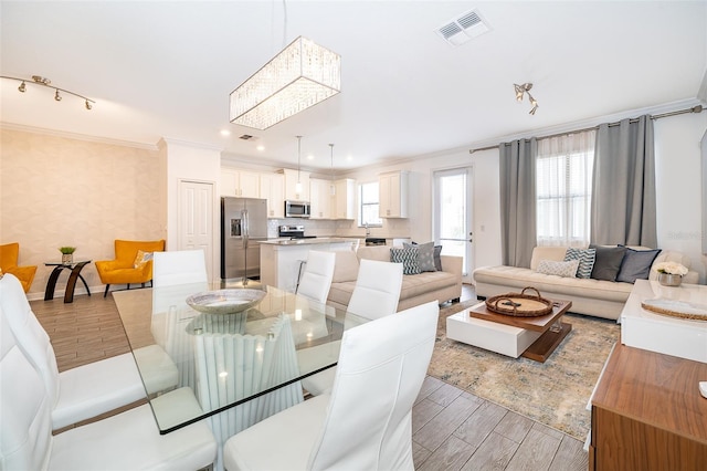 dining space with ornamental molding, light hardwood / wood-style floors, and a notable chandelier