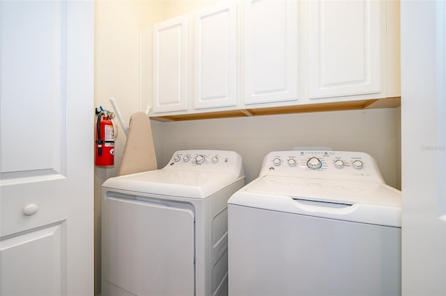 clothes washing area featuring separate washer and dryer and cabinets